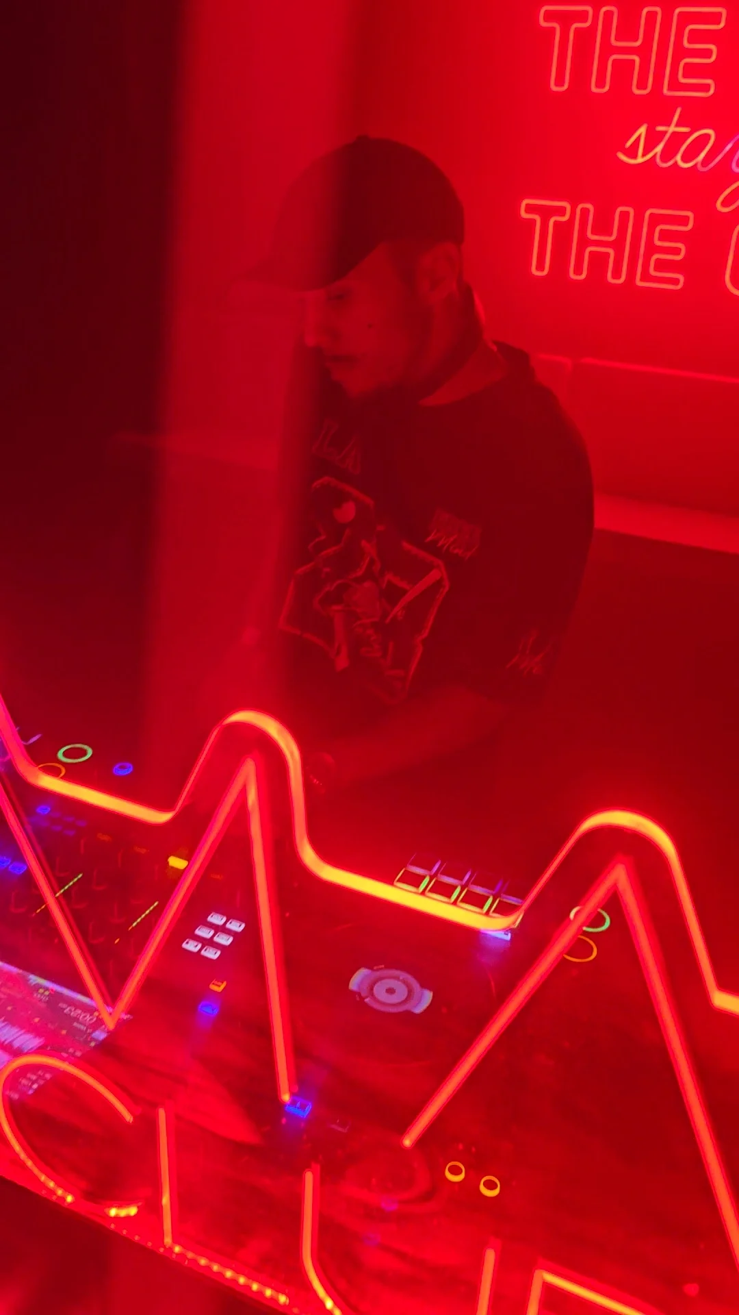 BassWare en la cabina de DJ bajo luces rojas.
