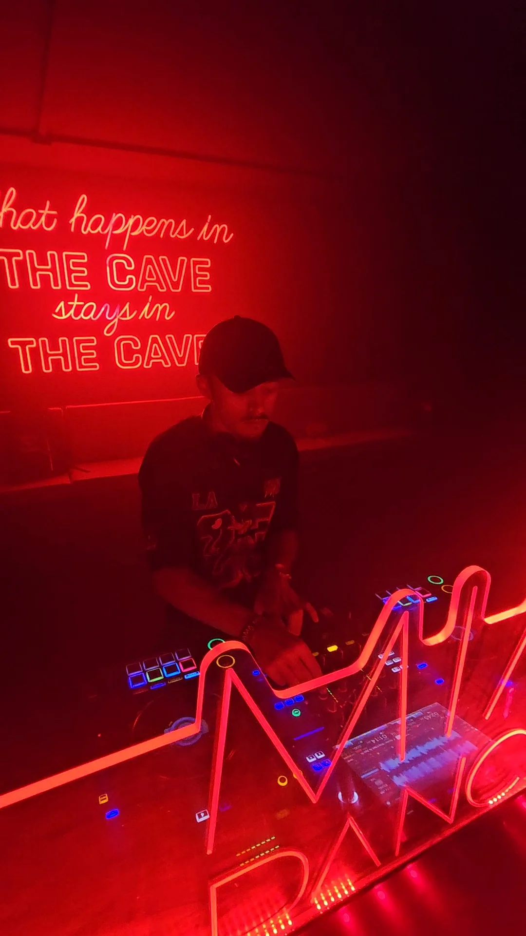 BassWare mezclando en los equipos de DJ, con iluminación roja.